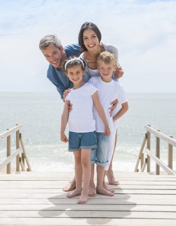 happy family standing on a wood pontoon in front of the sea in